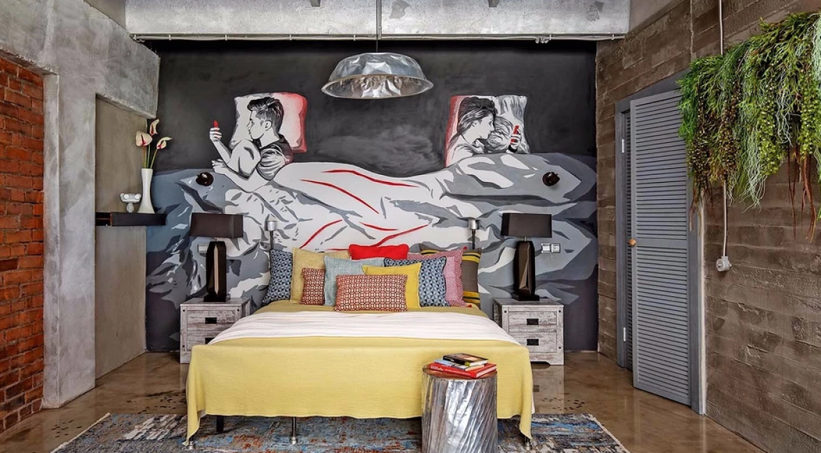 В спальне в глаза бросается не только яркая желтая кровать. За ней на стене изображено граффити. Это два человека, которые отвернулись друг от друга и проводят время в гаджетах. Автор граффити — социальный художник Слава ПТРК.